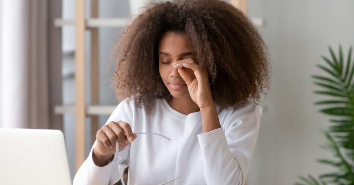 Girl rubbing eye tired from compute holding glasses