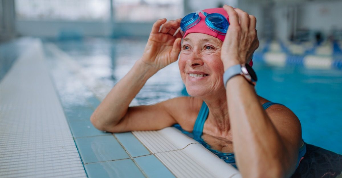 A female senior citizen with swimming goggles in a swimming pool.