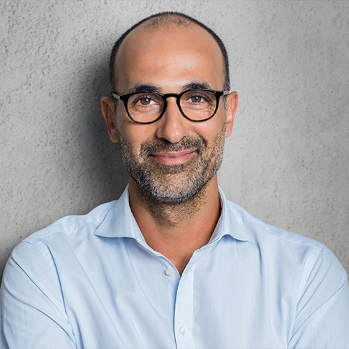 A man smiling, wearing glasses.