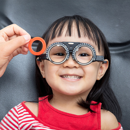 A child at an ophthalmology exam testing out glasses lens.