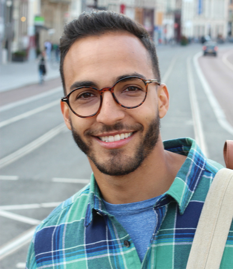 Man wearing eyeglasses smiling in the city.