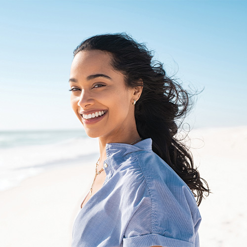 A lady with her wind blowing the wind at the beach.