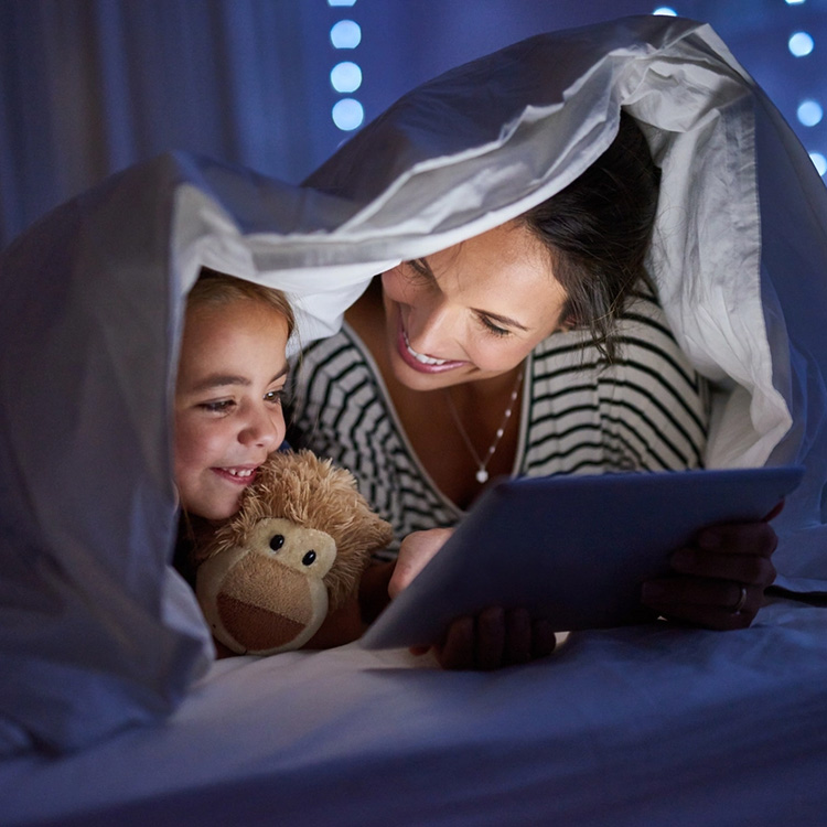 Mother and daughter looking at iPad screen at nighttime together.