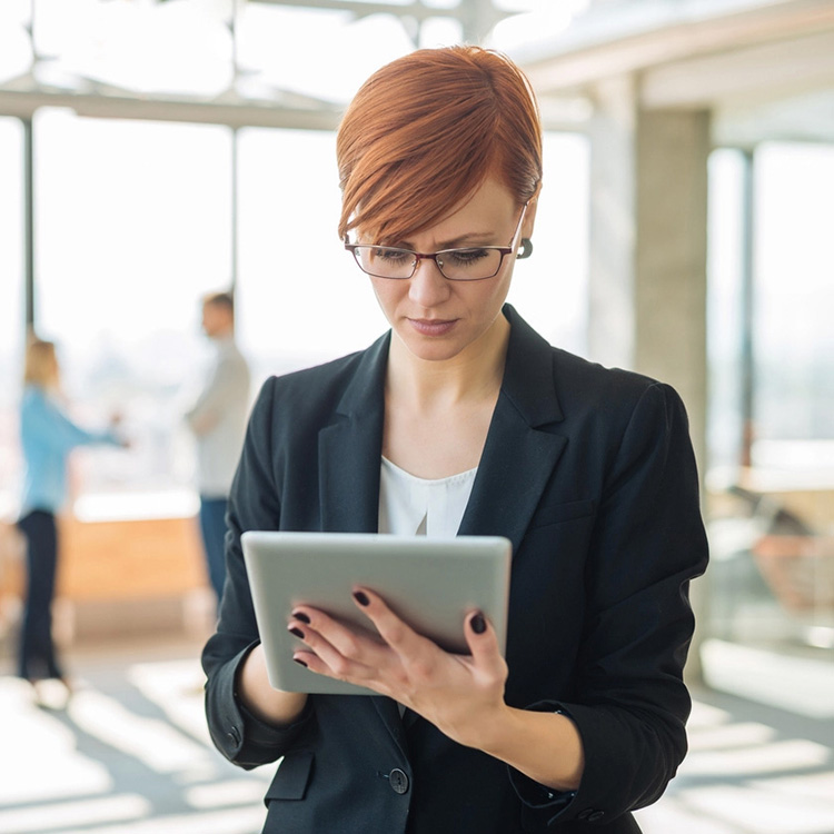 A woman in her profession using an iPad while wearing blue light glasses to protect her eyes from strain.