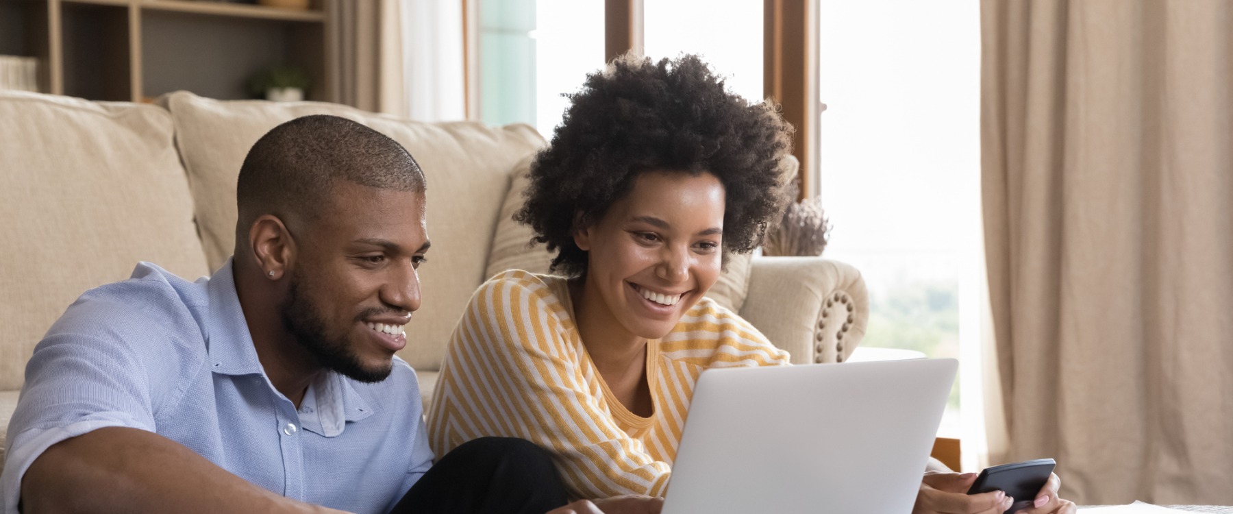 Happy young black couple using laptop