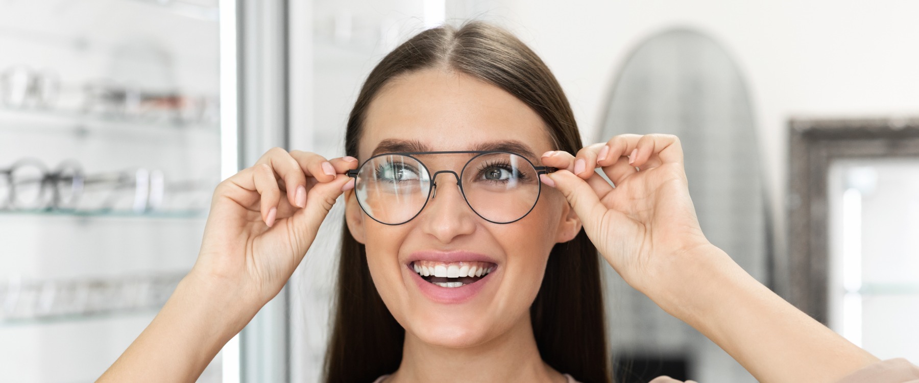 Happy young woman trying on glasses