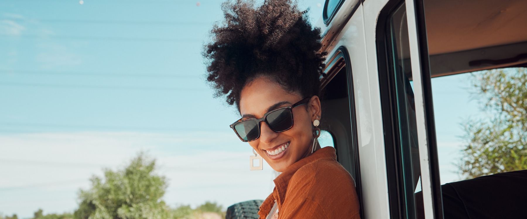 Happy woman on road trip smiling outside of car