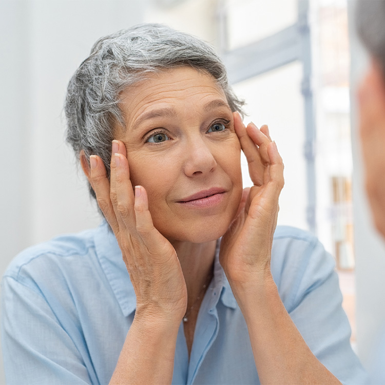 Woman looking at her eyes through a mirror.