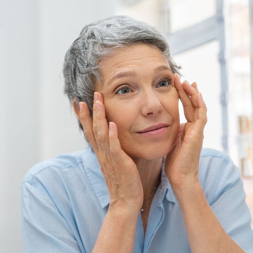 Woman looking at her eyes in mirror