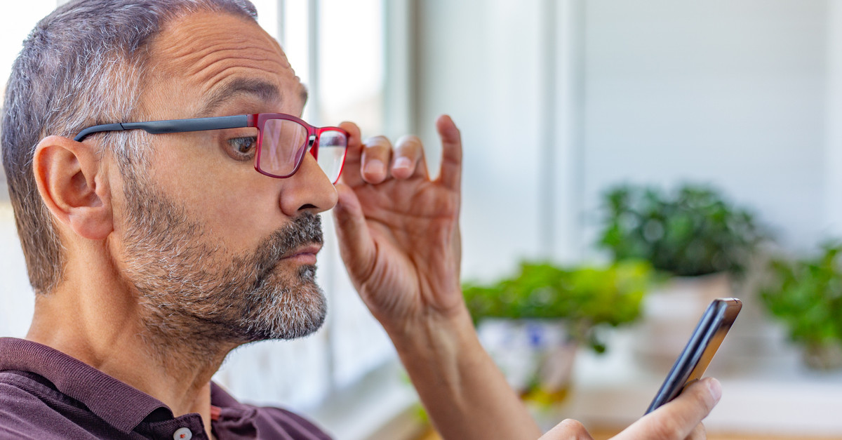 Man using glasses to look at phone